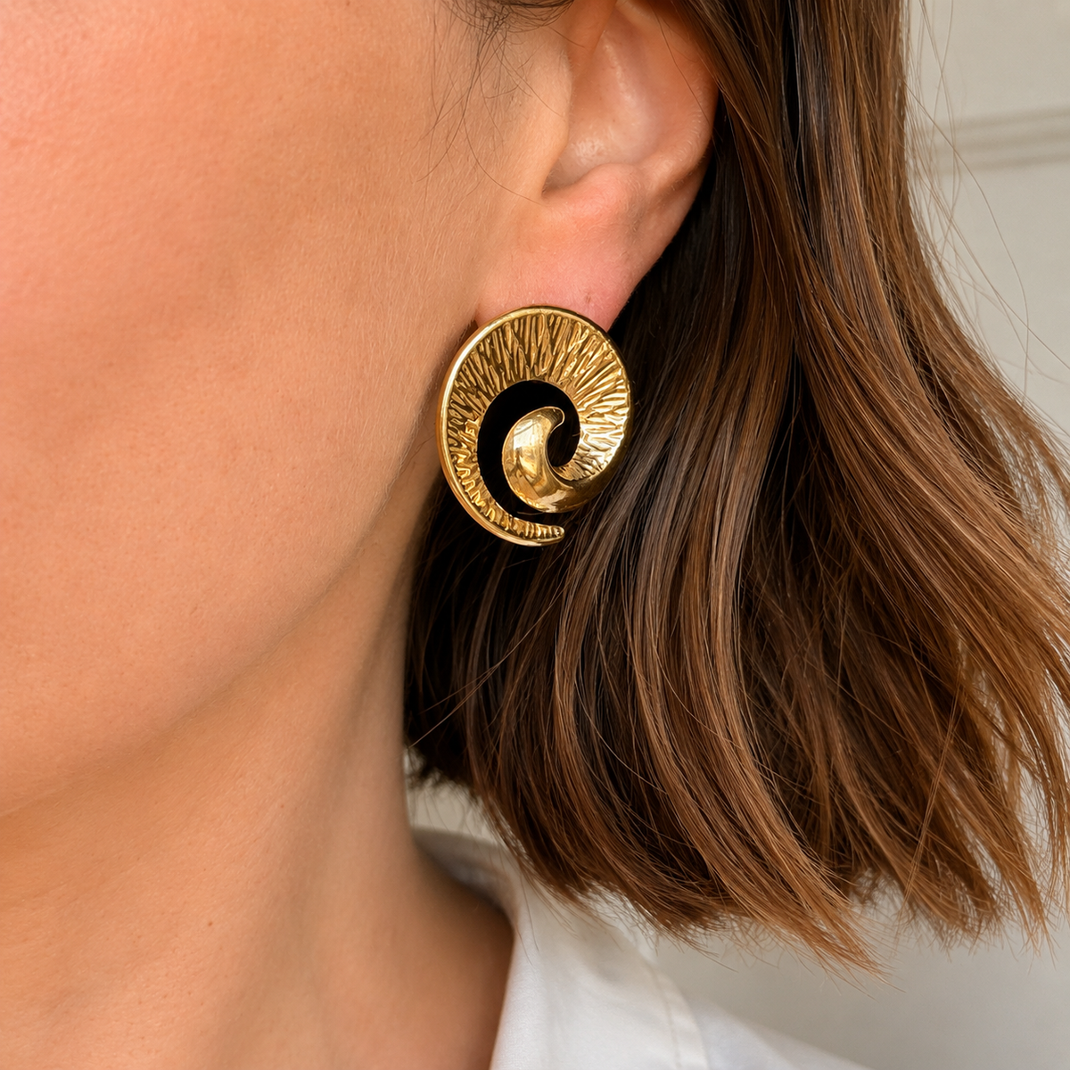 Gold swirl statement stud earrings on display