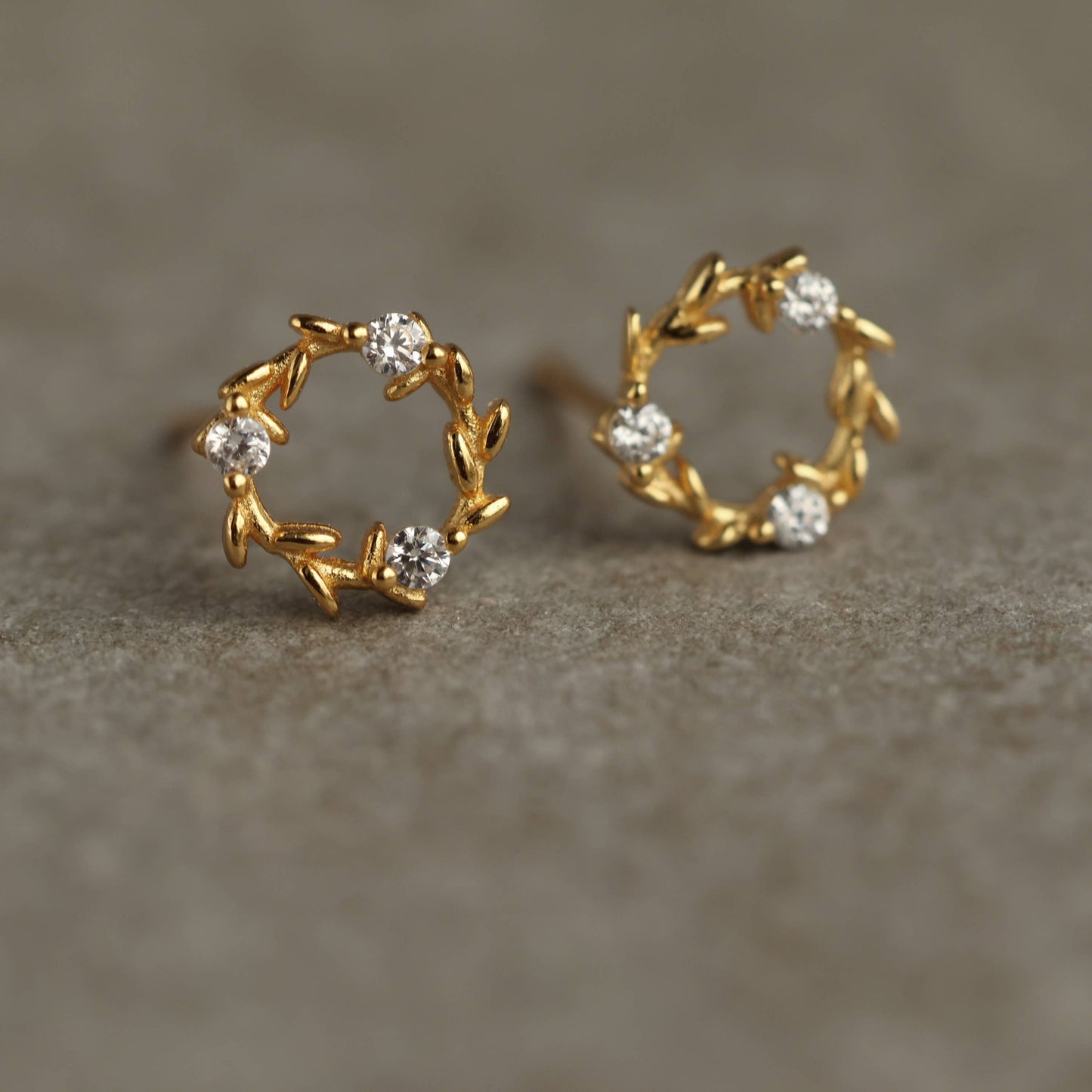 These charming and unusual stud earrings feature a miniature laurel leaf design, with cubic zirconia crystals formed to create a fluid, Art Nouveau inspired design. The earring posts and butterfly backs are gold plated 925 sterling silver. 