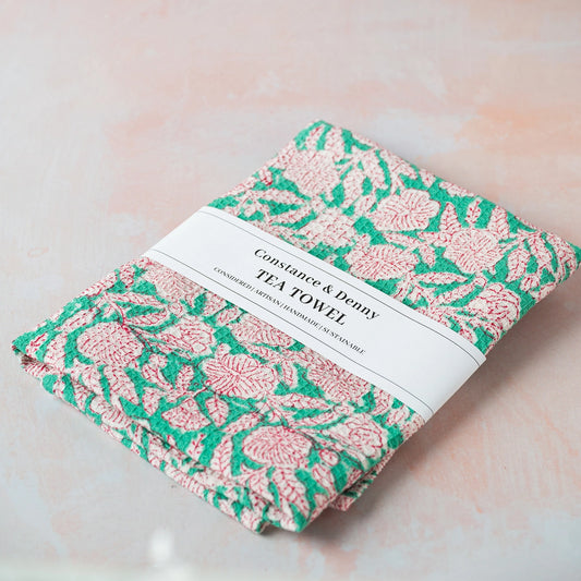 Tea towel with pink and green floral pattern on a light background