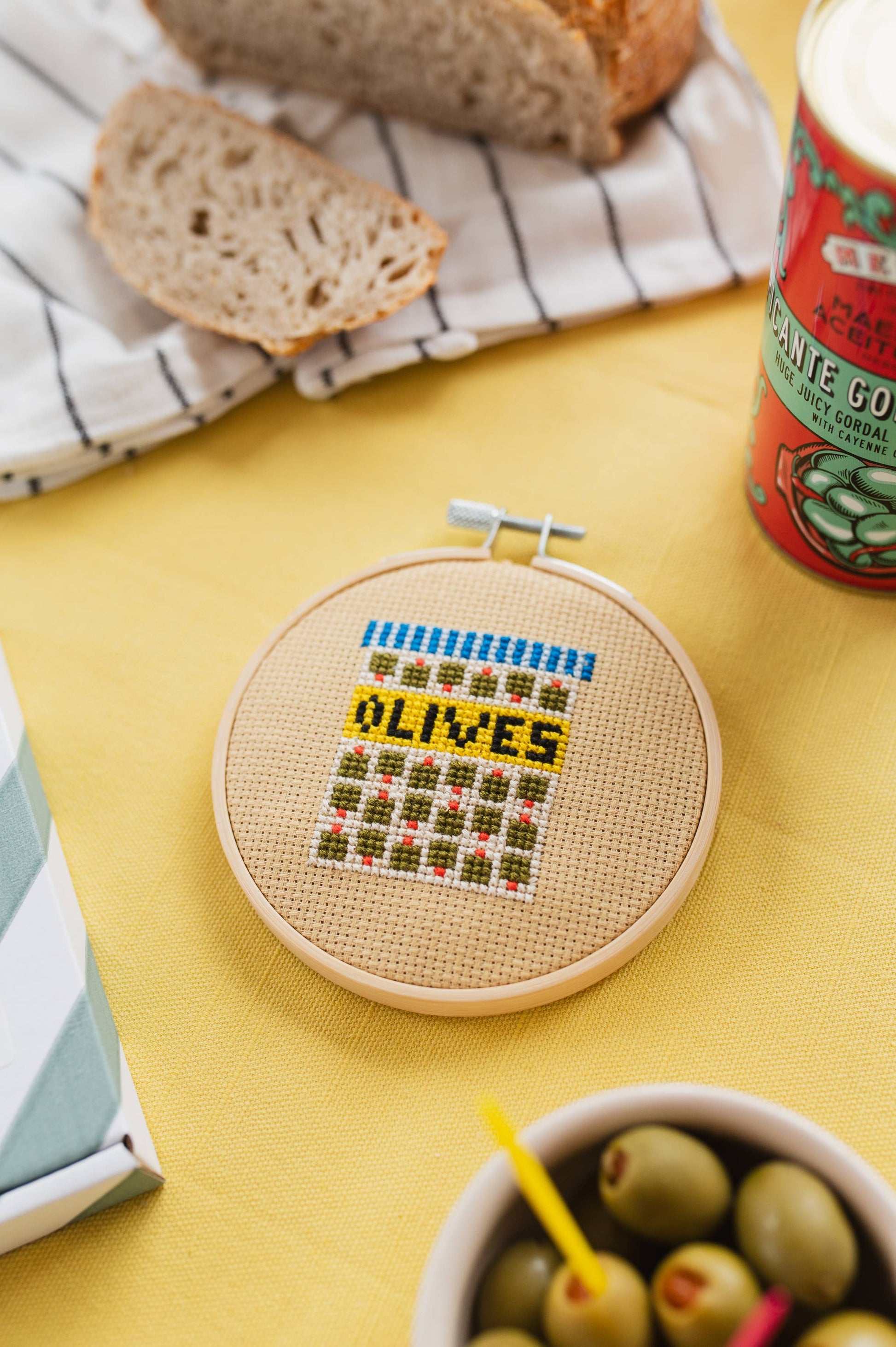 Finished Olives Cross Stitch artwork in a wooden hoop, showcasing the charming olive branch design, perfect for home decor.