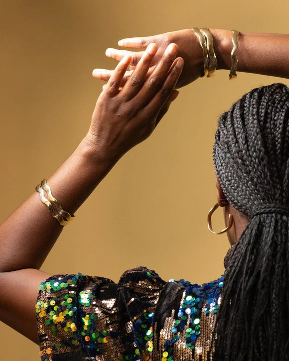 Gold-tone recycled brass wavy bangle bracelet, handcrafted in Kenya by husband-and-wife artisans, Anton & Benta.