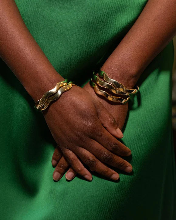 Gold-tone recycled brass wavy bangle bracelet, handcrafted in Kenya by husband-and-wife artisans, Anton & Benta.