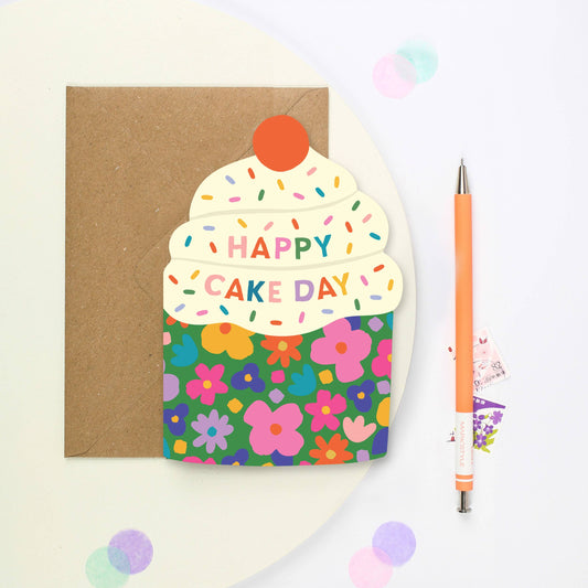 Indulge in sweetness and charm with our delightful Cupcake-Shaped Birthday Card nestled in a floral case. This unique greeting card, crafted in the shape of a delectable cupcake with the caption “Happy Cake Day” in rainbow colour writing. This bold greeting card features lots of white frosting, topped with sprinkles and a vibrant red cherry, adding a touch of whimsy to any birthday celebration. With its intricate details and elegant floral case, it's a perfect choice for conveying warm birthday wishes with 