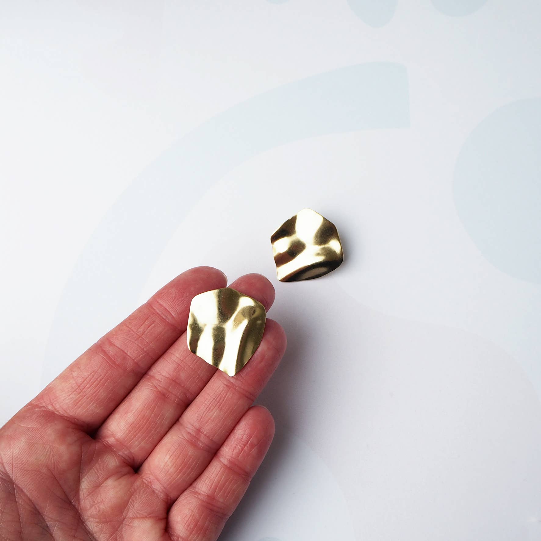 Handmade wavy gold statement studs showing sterling silver posts