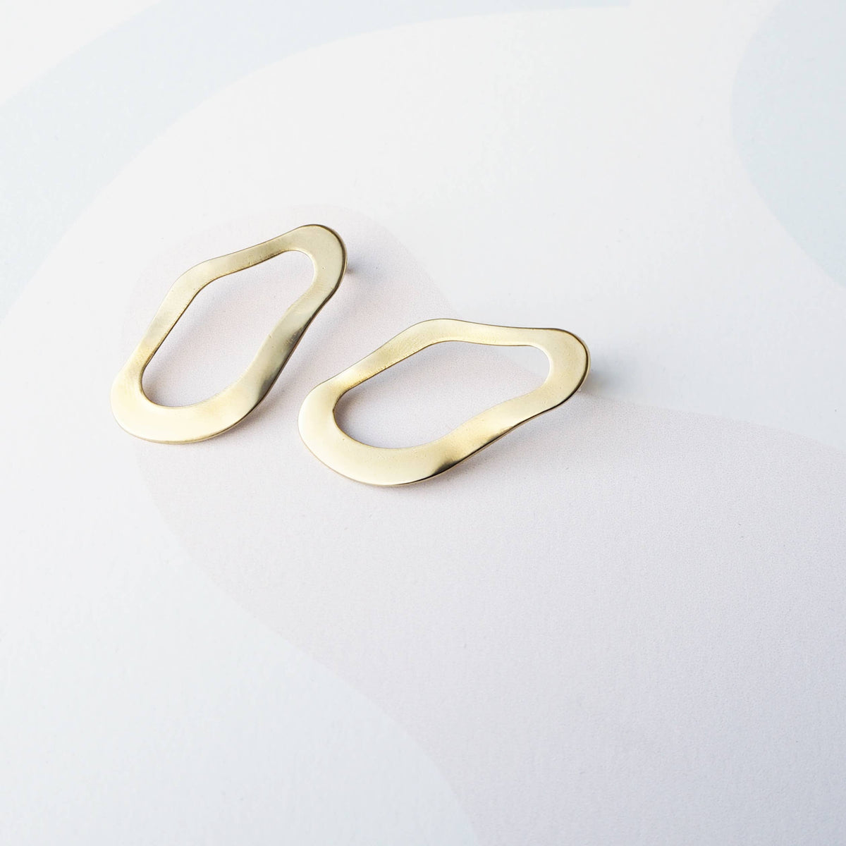 Sculptural gold drop earrings on model