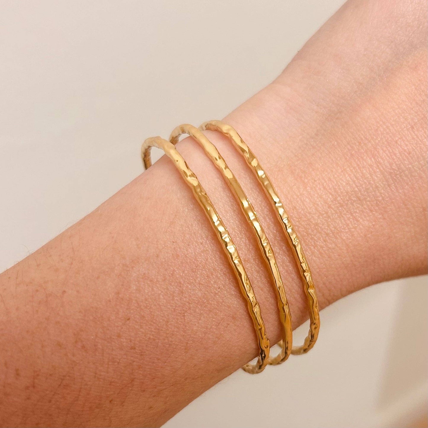 A hammered trio bangle in a polished gold finish. 18k gold plated bracelet. Light and comfortable enough to wear all day, and works well as a stacking piece for a more eye-catching look.