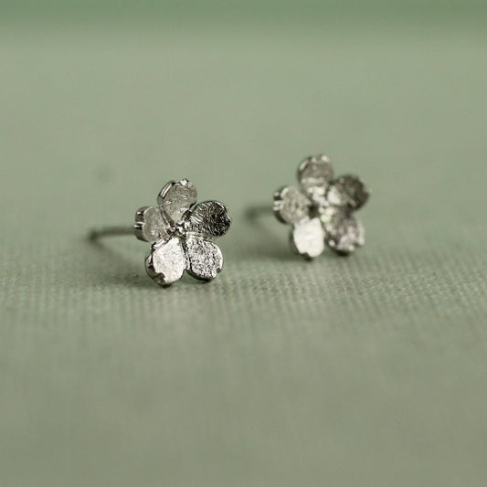 These sweet and dainty stud earrings feature a pair of tiny forget me not flowers, made from Sterling Silver with a subtle brushed texture. The earrings measure 9mm in diameter. 