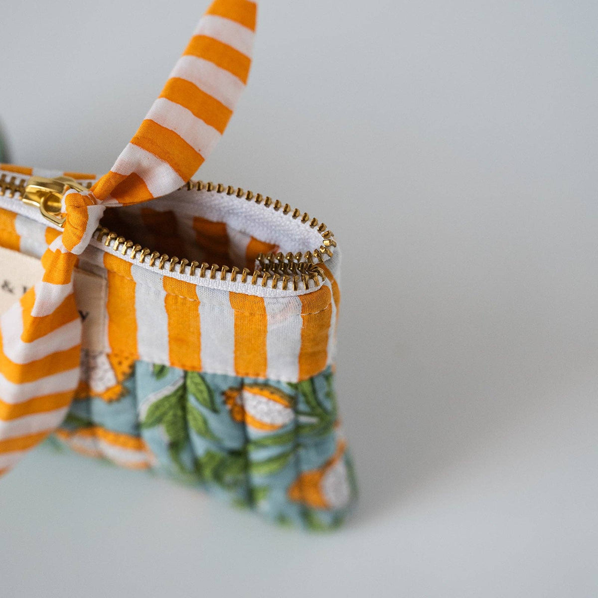 Close-up of the brass zip and striped pull on the quilted cotton pouch