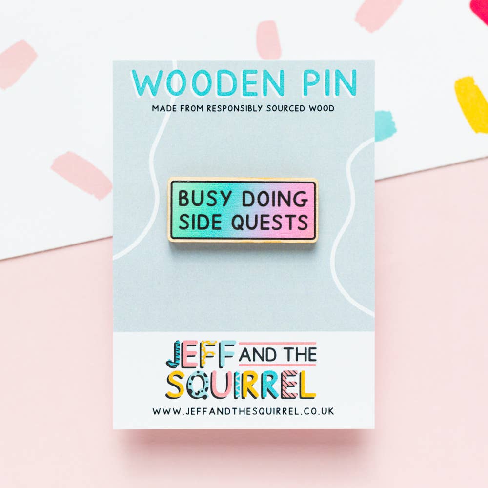 Busy Doing Side Quests wooden pin displayed on a recycled backing card