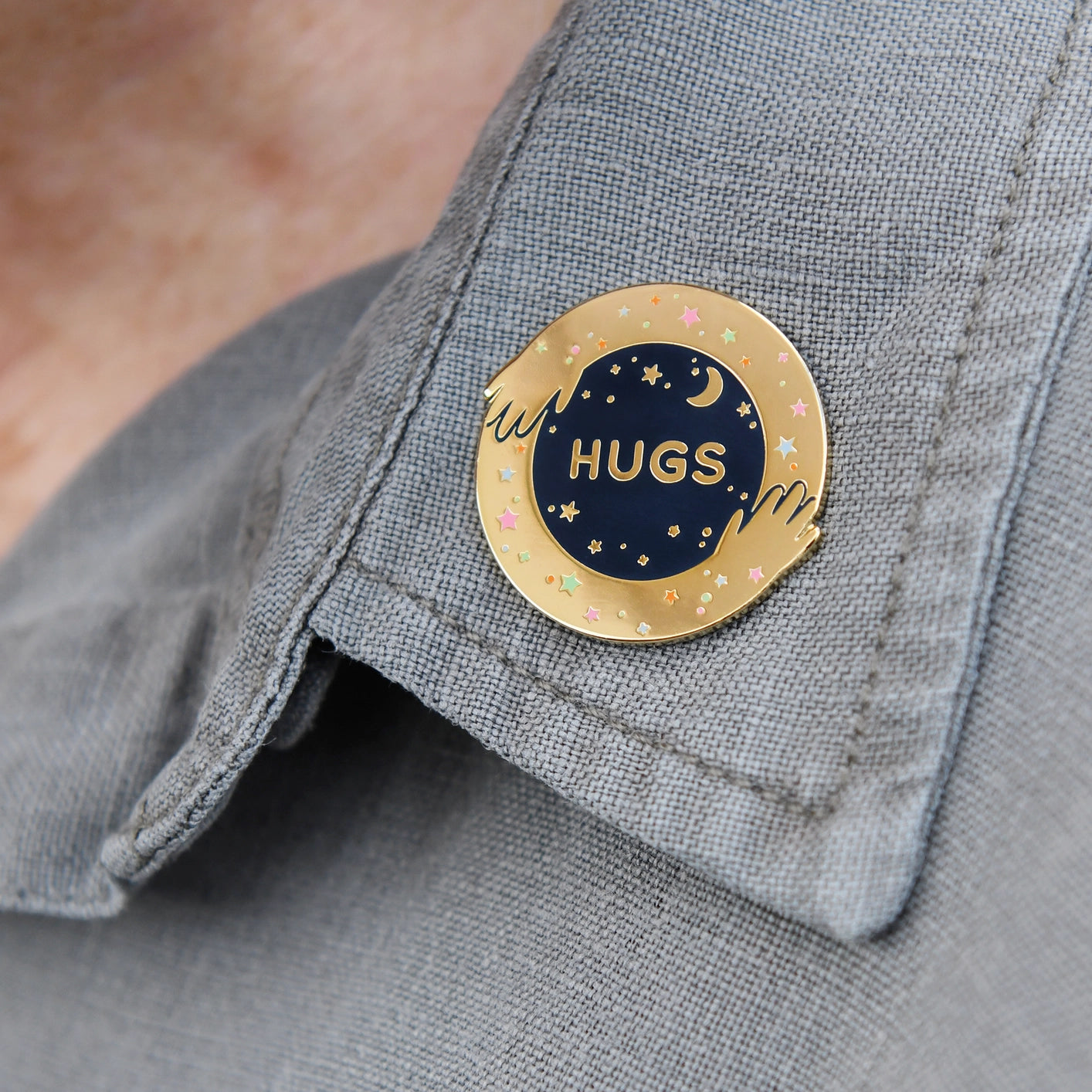 Pin with 'HUGS' text on a gray shirt