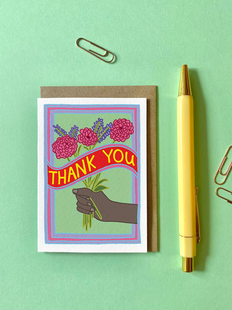 Mini Thank you Card. Thank You! Featuring a hand and a colourful bunch of flowers. With the words THANK YOU across the middle of the card in bold yellow writing.