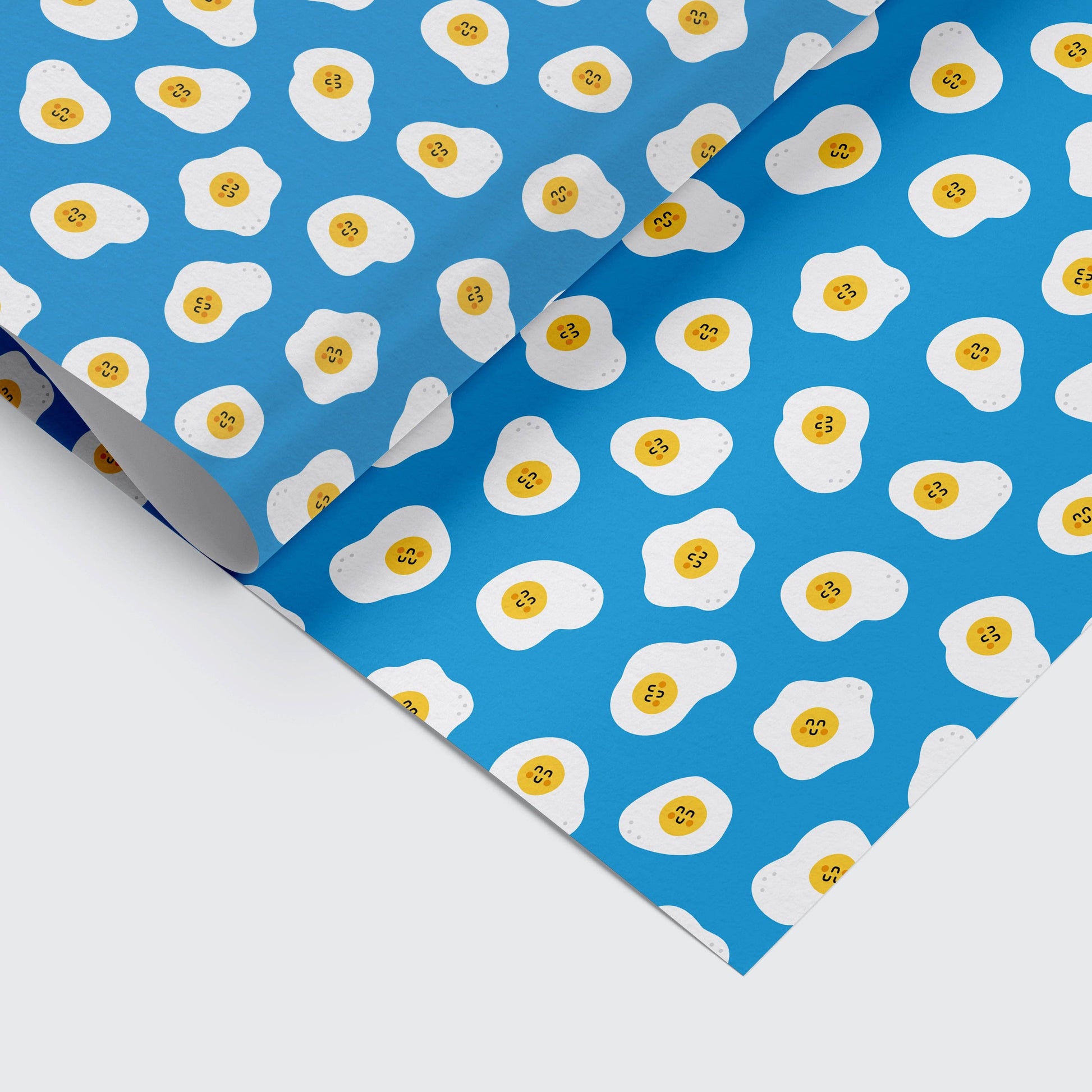 Vibrant blue wrapping paper featuring cute fried eggs with happy faces