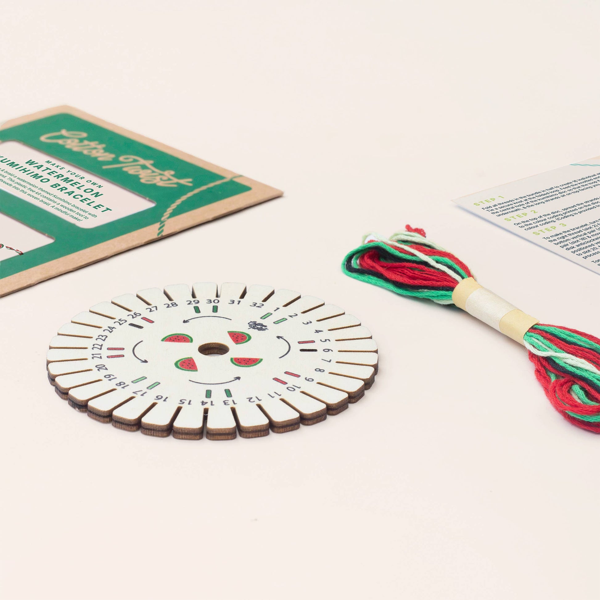Watermelon themed Kumihimo bracelet being woven on a wooden disc