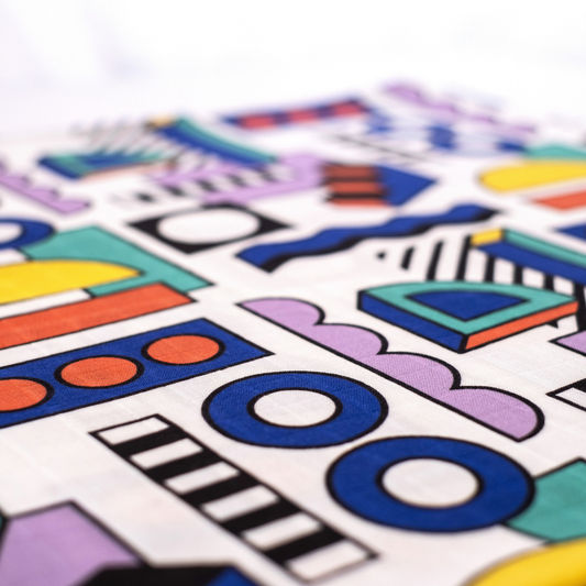 Etta Loves Walala organic sensory muslin, unfolded, showcasing vibrant geometric 'Shapes' pattern