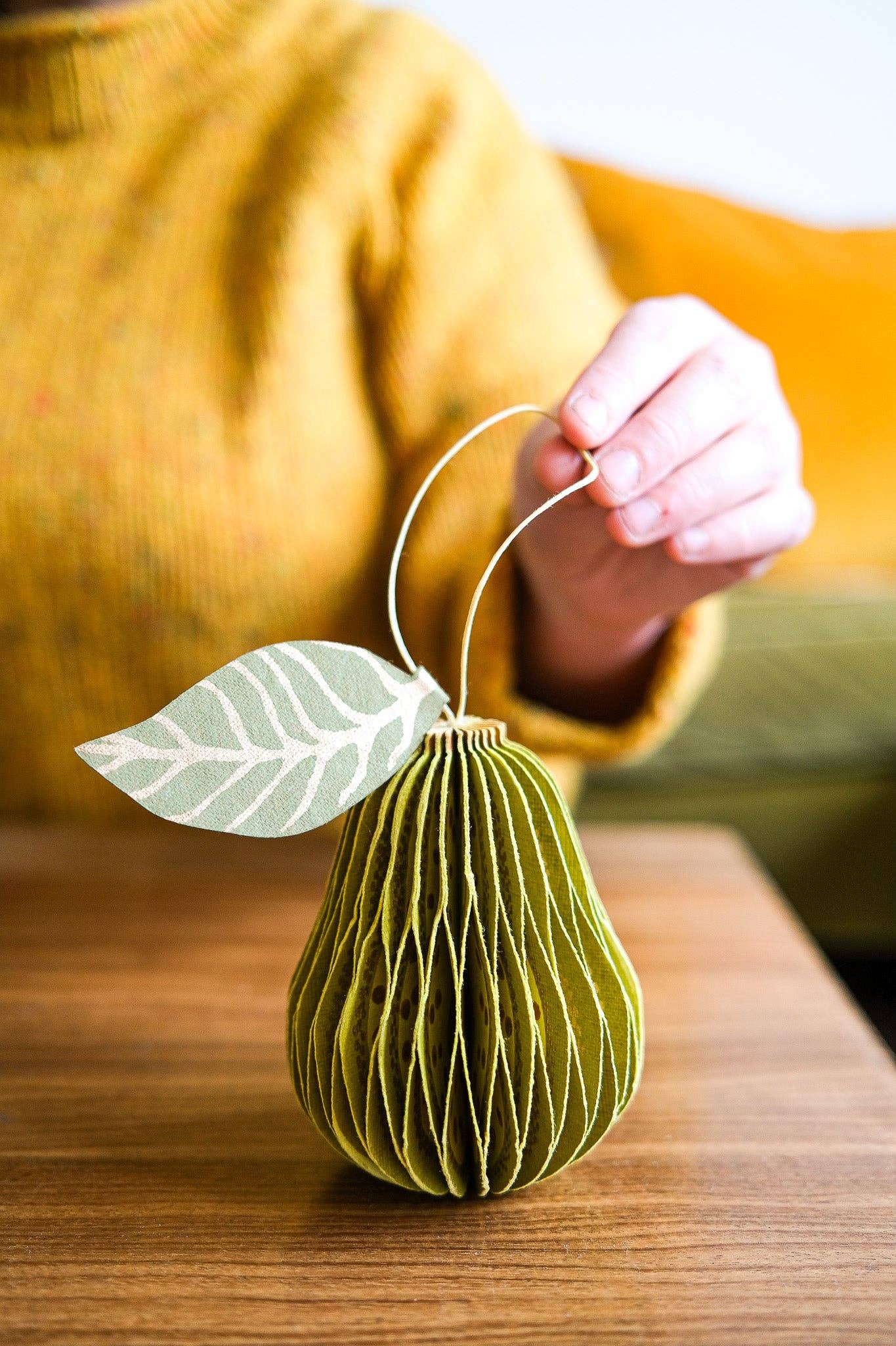 Flat recycled cotton paper pear ornament before unfolding, in packaging