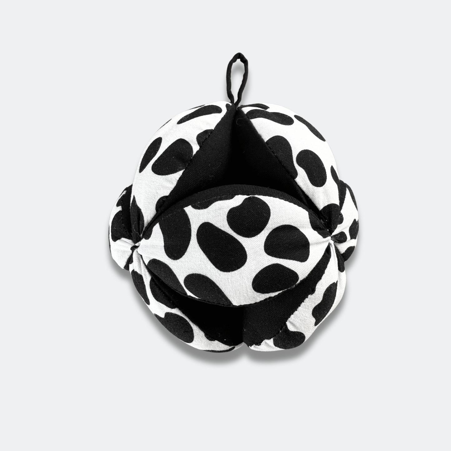 Sensory grasp ball in Dalmatian print by Etta Loves, 12cm diameter, made from organic cotton with segments for grasping and a central bell for sensory play.