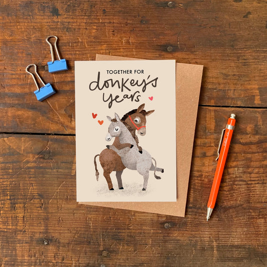 A6 greeting card with a colourful donkey illustration by Emily Nash and ‘Donkey’s Years’ caption, printed on  sustainably certified matte card with recycled kraft envelope.
