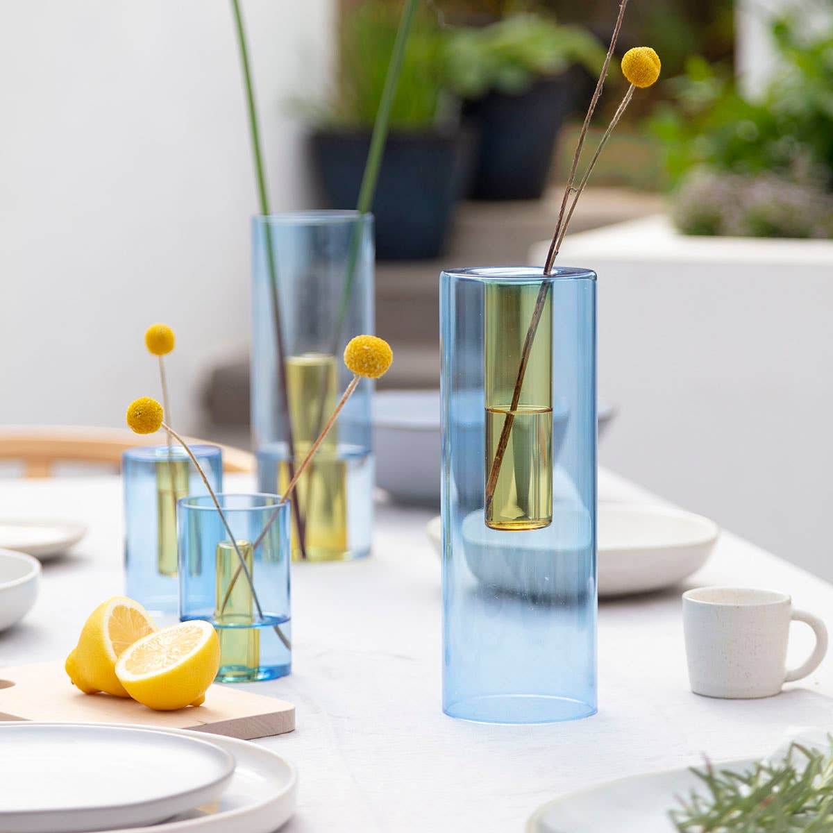 Set of blue and green gradient vases with floral arrangements on a table.