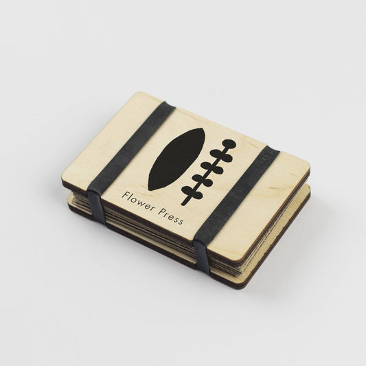 Pocket Size Flower press by Studio Wald. Black and white images of flowers on maple veneered sustainably sourced wood. Made in the UK.  Fasten using the elastic bands and pop the press in your pocket. - The press comes complete with 5 sheets of corrugated card and 8 of sugar paper to give ample space to press flowers. 