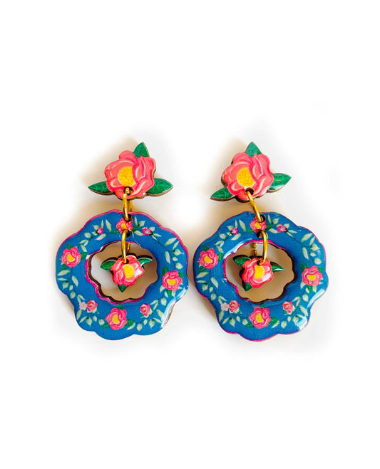 Blue floral flower drop earrings which are double dangle. With a with a mini flower in the middle compartment. Blue colour with pink hues and flowers. Laser cut wood and lacquered with clear resin.