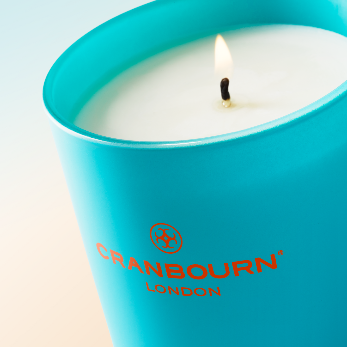 Lit candle. Soirée à Marrakech™, a woody oriental scent with dry spices and earthy tones, reflects Marrakech's richness. Top notes of bergamot, freshly grated nutmeg and carrot seed, leading to a heart of jasmine and cyclamen, supported by sandalwood, patchouli and an amber base. Handmade in the UK. Blue glass vessel.