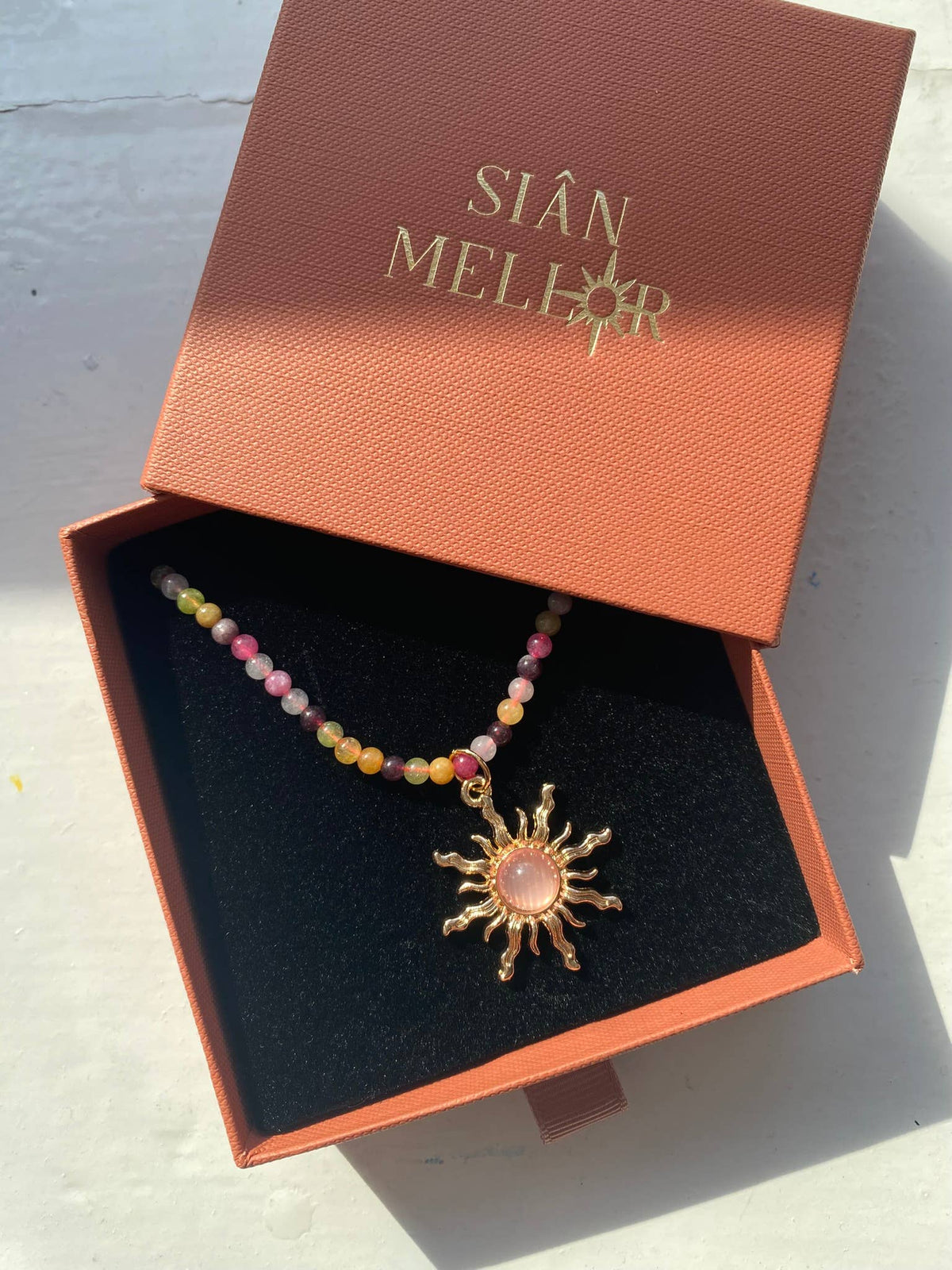 Close-up of the vibrant colourful beads and gold sun pendant