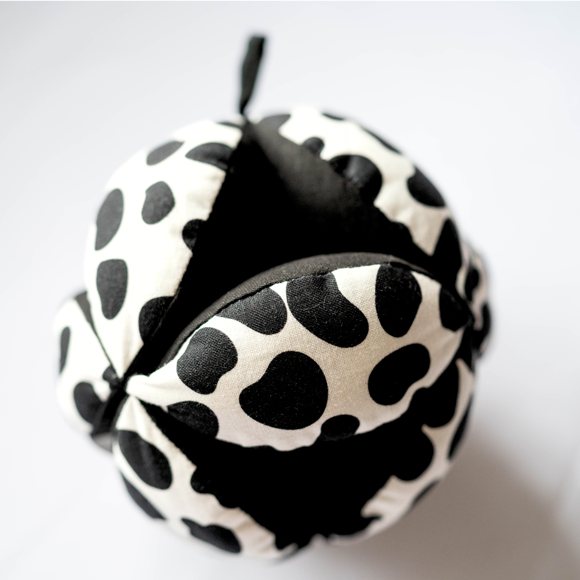 Sensory grasp ball in Dalmatian print by Etta Loves, 12cm diameter, made from organic cotton with segments for grasping and a central bell for sensory play.