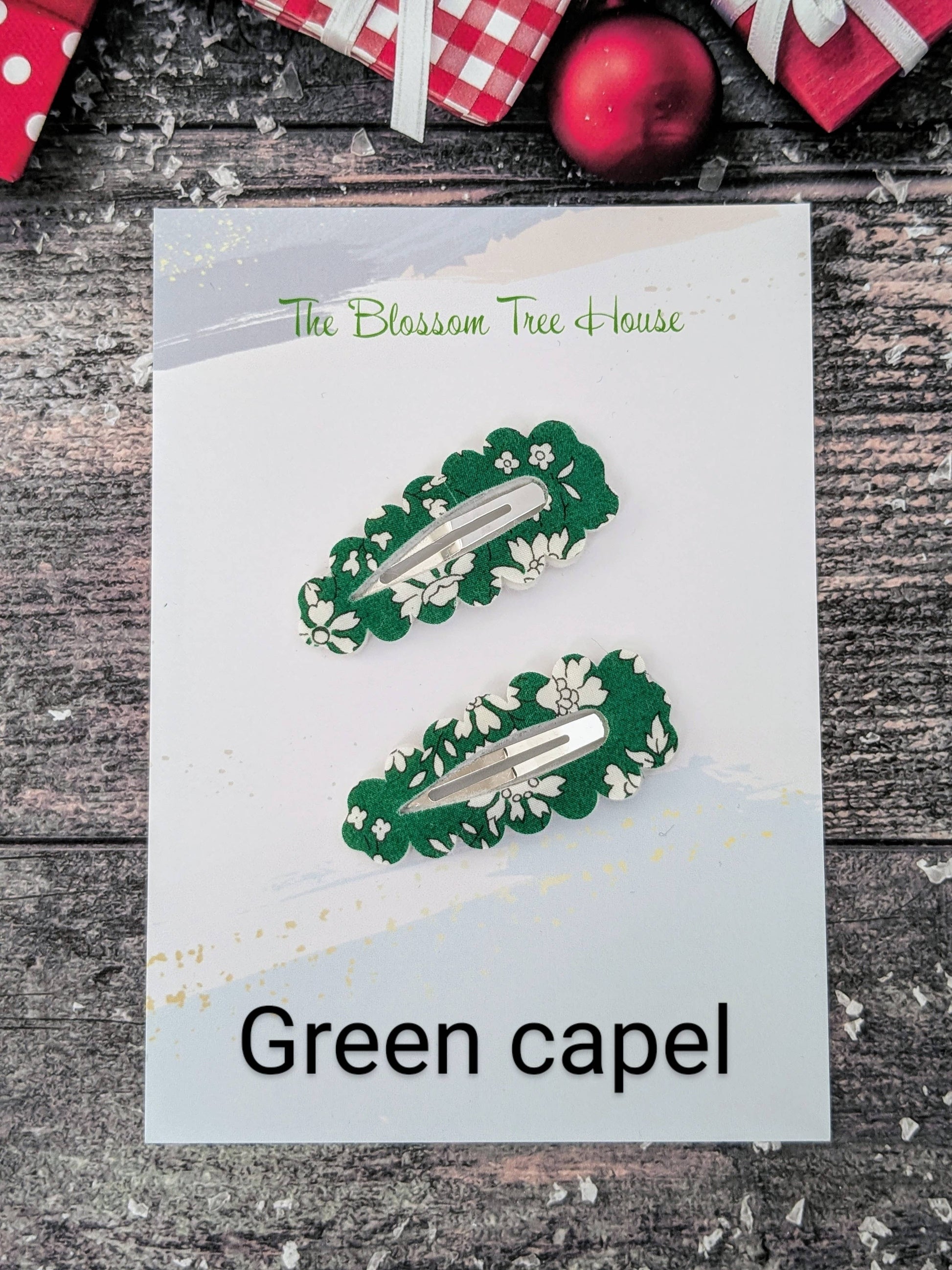 Green hair clips on a card with 'The Blossom Tree House' branding, set against a rustic wooden background.