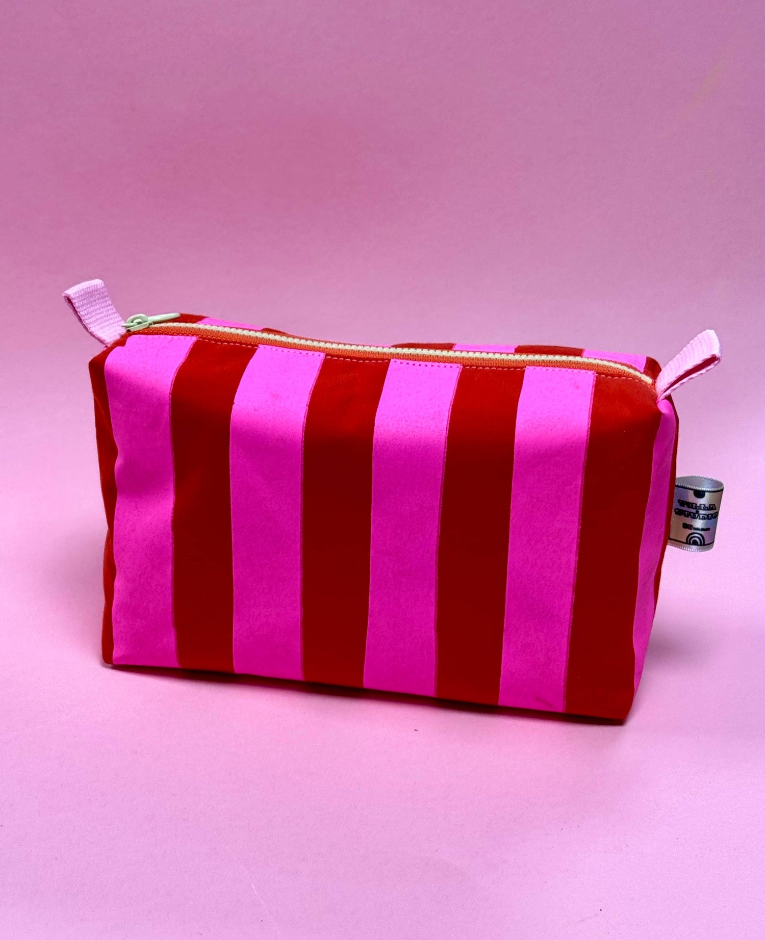 Close-up of pink and red stripe hand-printed wax cotton boxy pouch, fully lined.