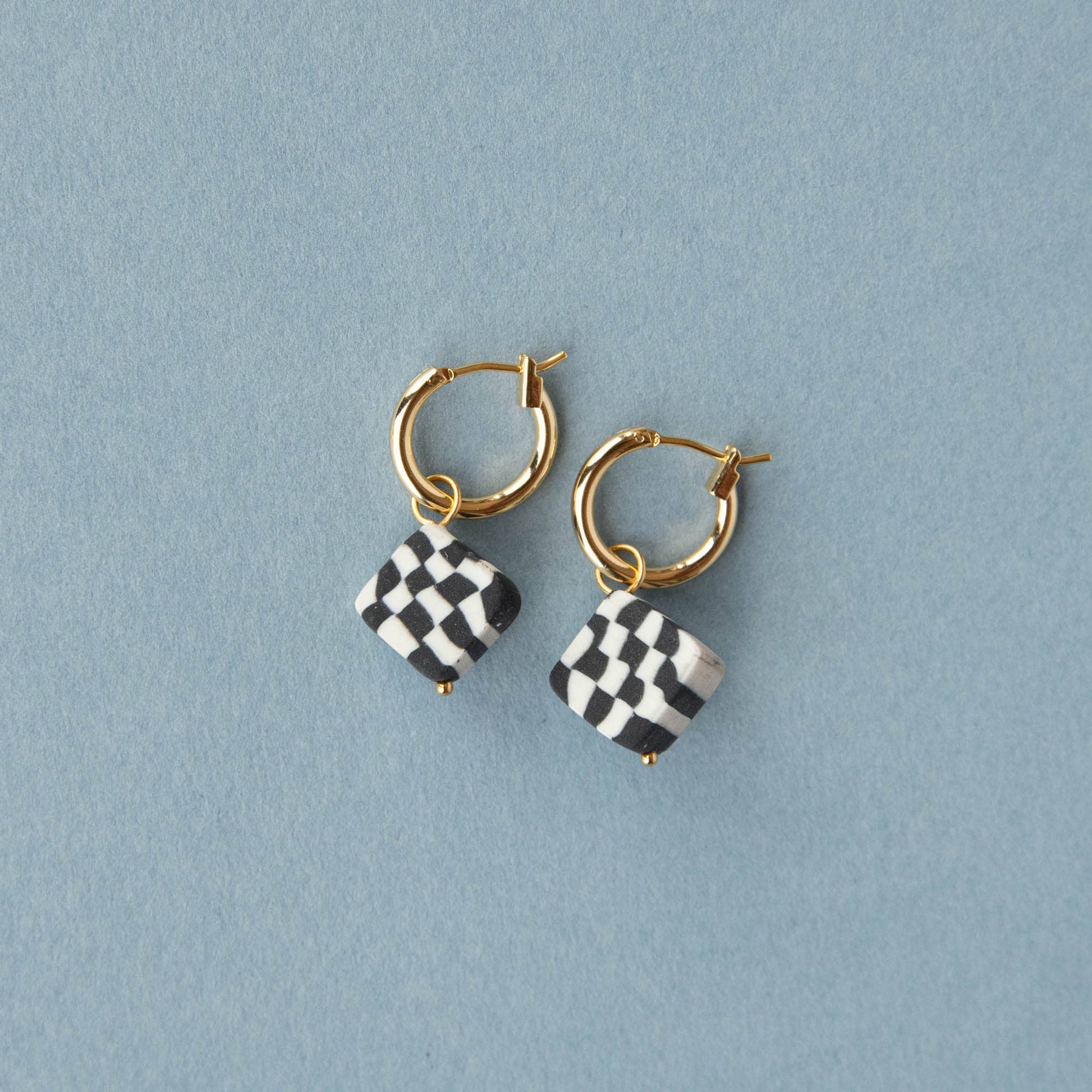 Close-up of Bits Diamond Clay Charm Hoop Earrings, showcasing the playful monochrome checkerboard pattern and gold-plated nickel-free hoops.