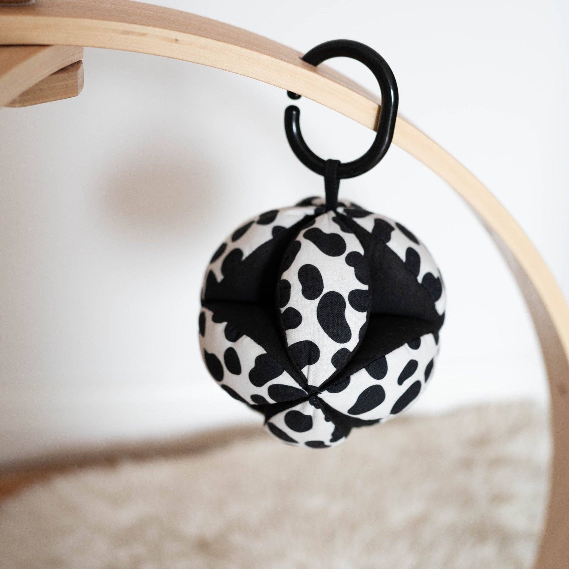 Sensory grasp ball in Dalmatian print by Etta Loves, 12cm diameter, made from organic cotton with segments for grasping and a central bell for sensory play.