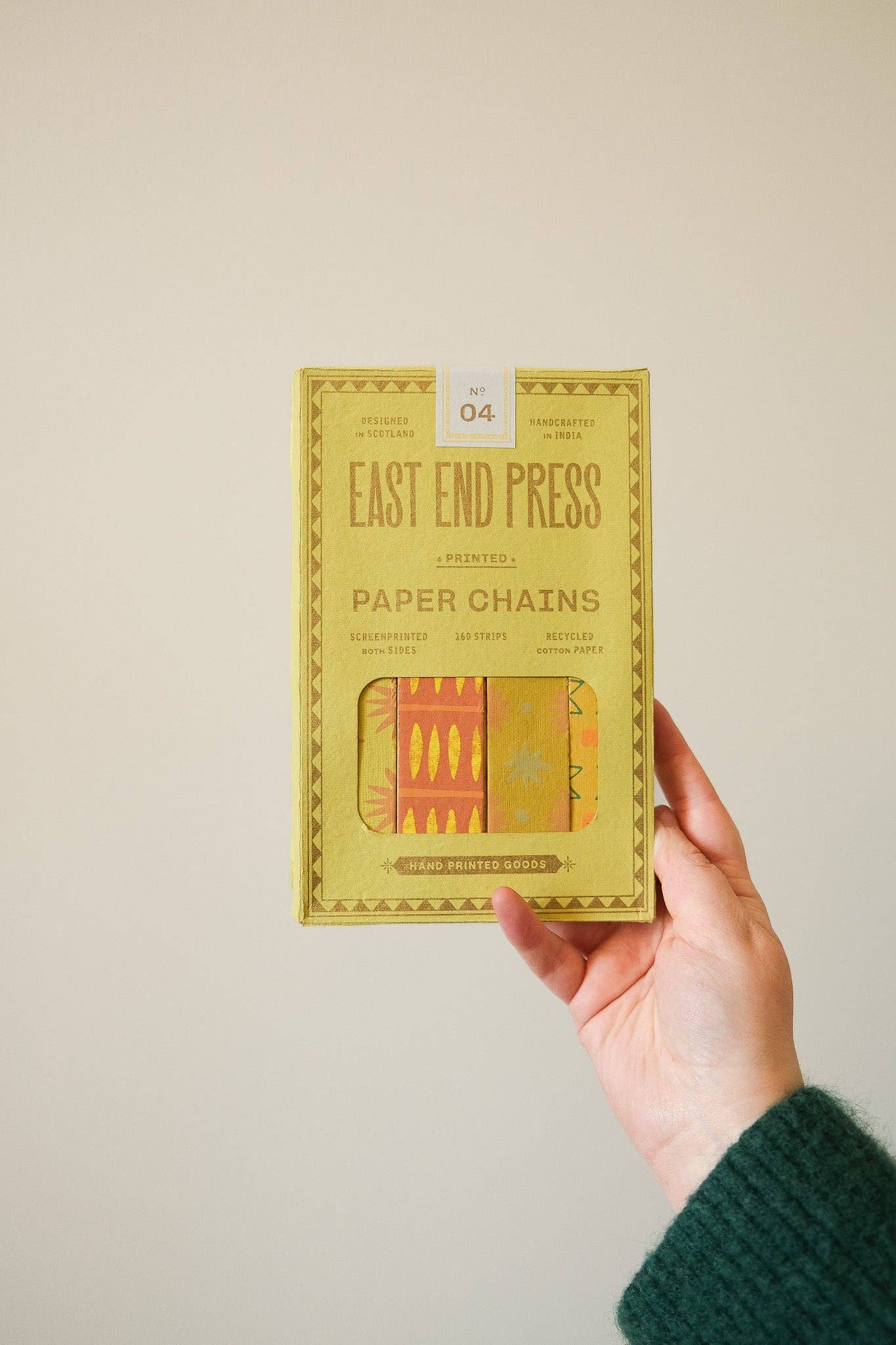 Stack of yellow and green patterned recycled paper chain strips