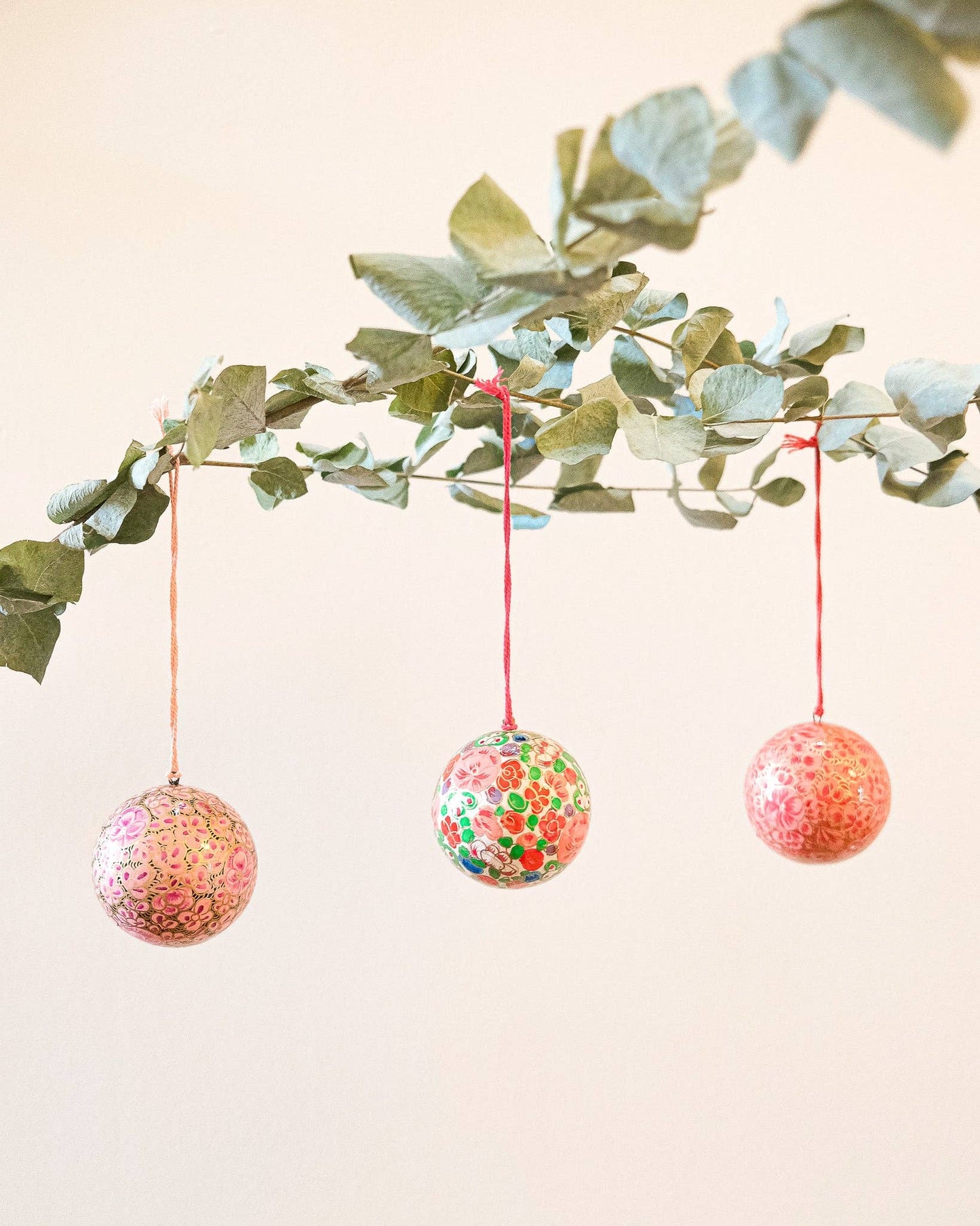 Collection of eco-friendly papier mâché baubles, including crimson flower