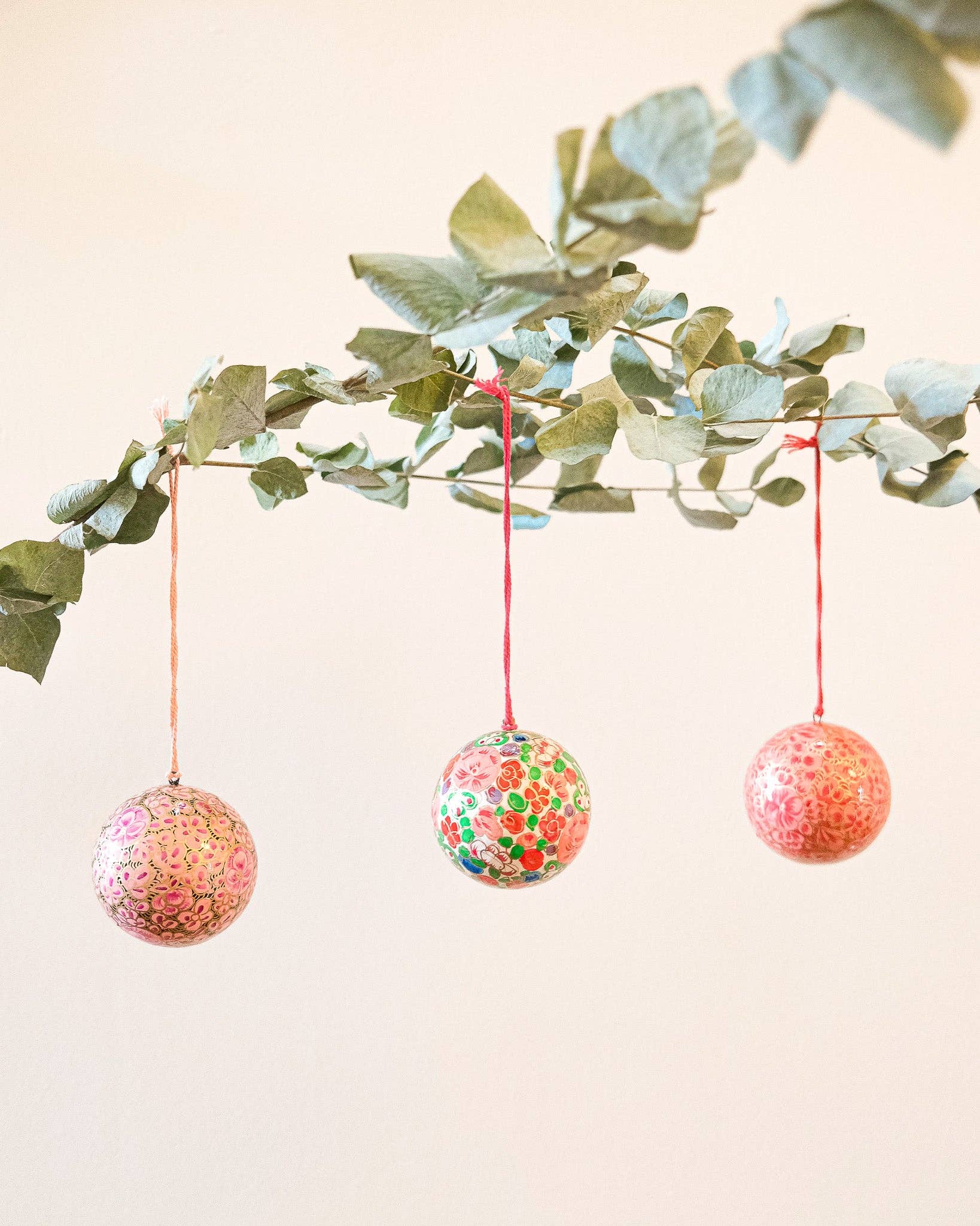 Collection of eco-friendly papier mâché baubles, including crimson flower