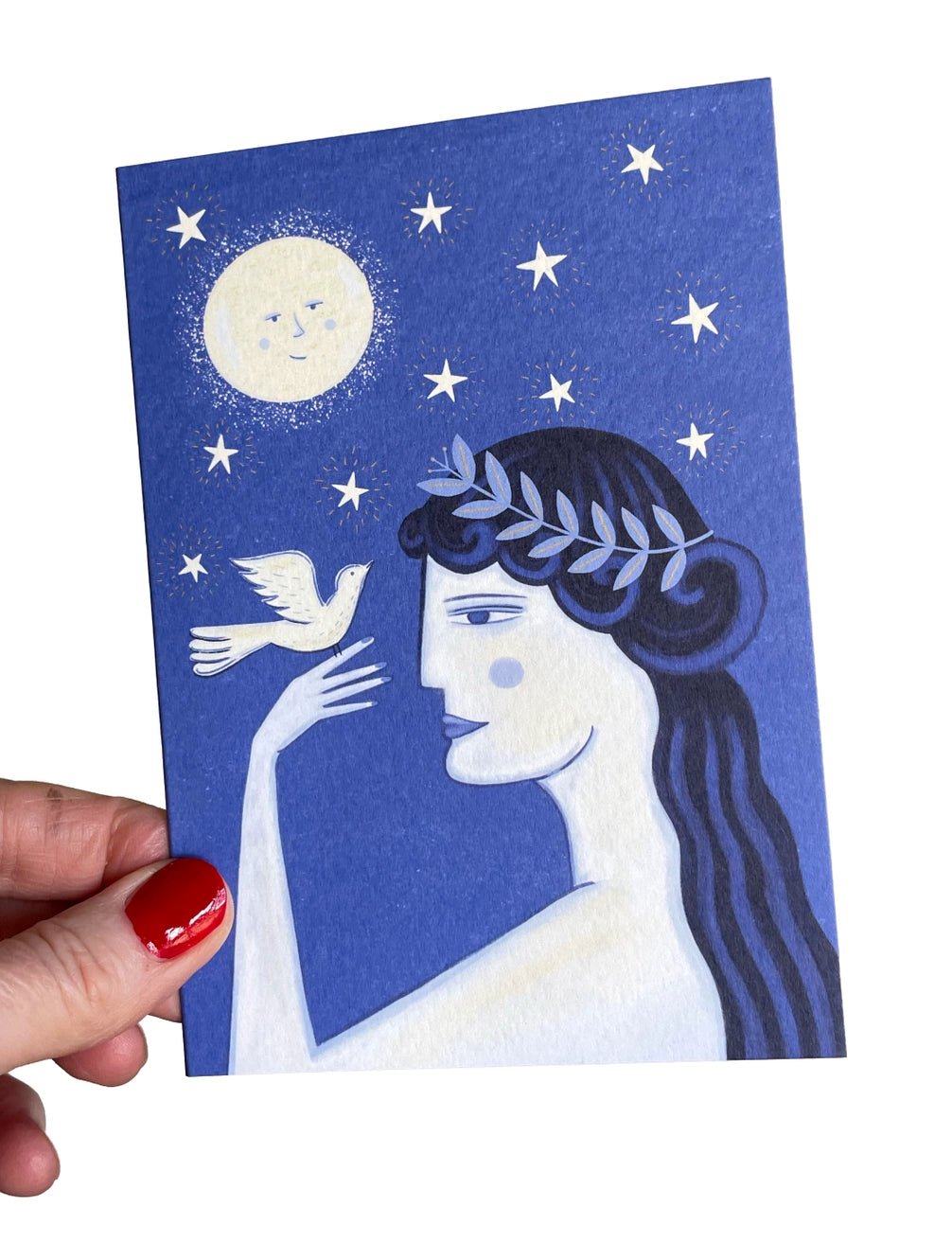 Greeting card with a stylized illustration of a woman with a dove and stars on a blue background, held by a hand.