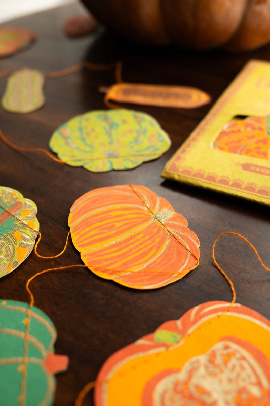 Handmade autumn squashes paper sewn garland hanging on a wall