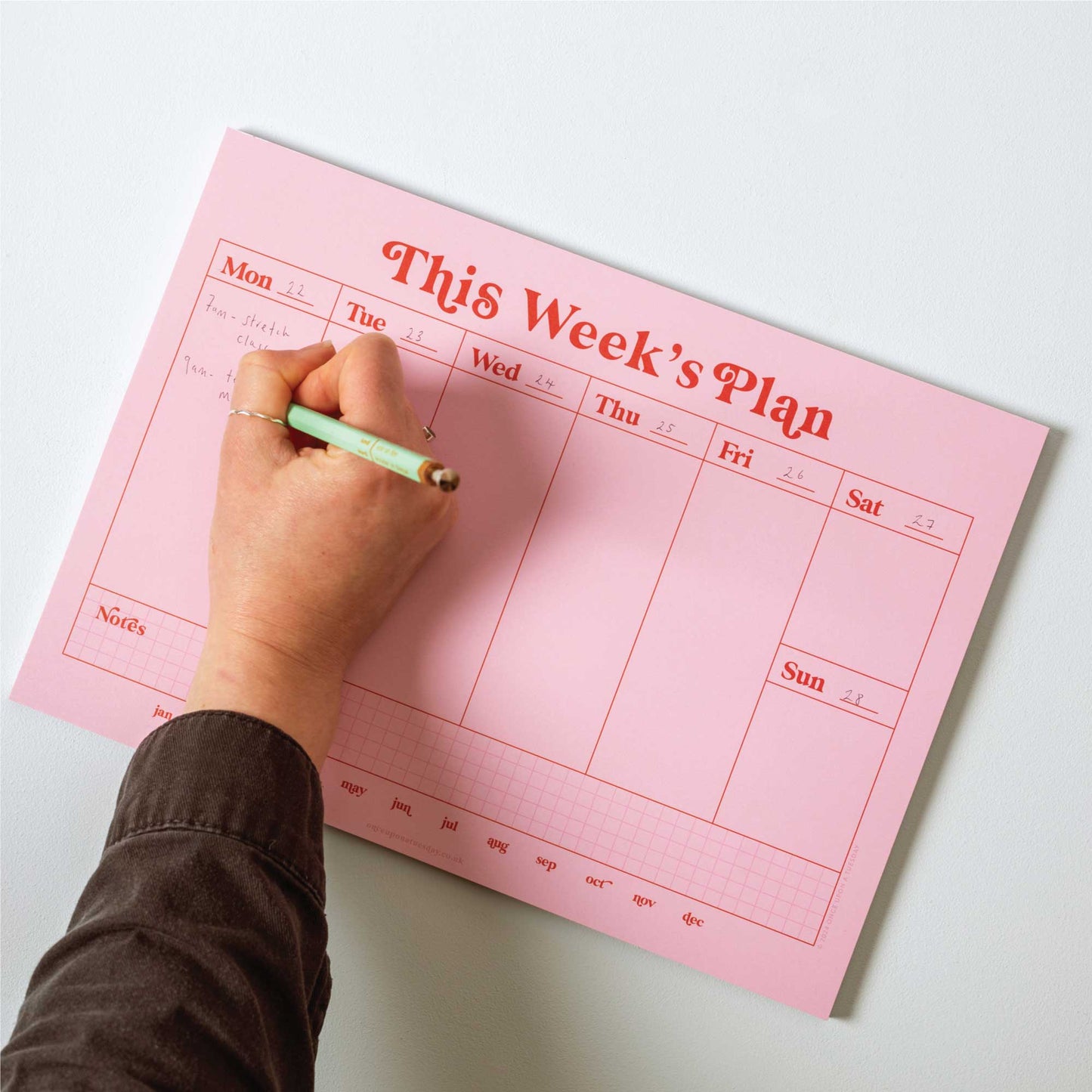 A4 Pink & Red Weekly Planner Pad being used for meal planning on a kitchen counter.