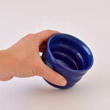 Handcrafted Ripple Beaker in Blue. Handcrafted from stoneware clay, this colourful ceramic beaker with distinctive ripple texture is ideal for your morning coffee, a wine with friends or even a good old cup of water. The quirky rippled form provides a playful aesthetic whilst also being extremely ergonomic to hold, perfect for slotting your fingers comfortably into the grooves. 7 cm high and 9cm wide at the rim.