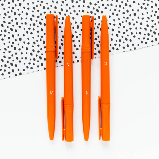 Close-up of the 'Organised As Fuck' orange eco pen, highlighting its recycled plastic barrel and twist mechanism.