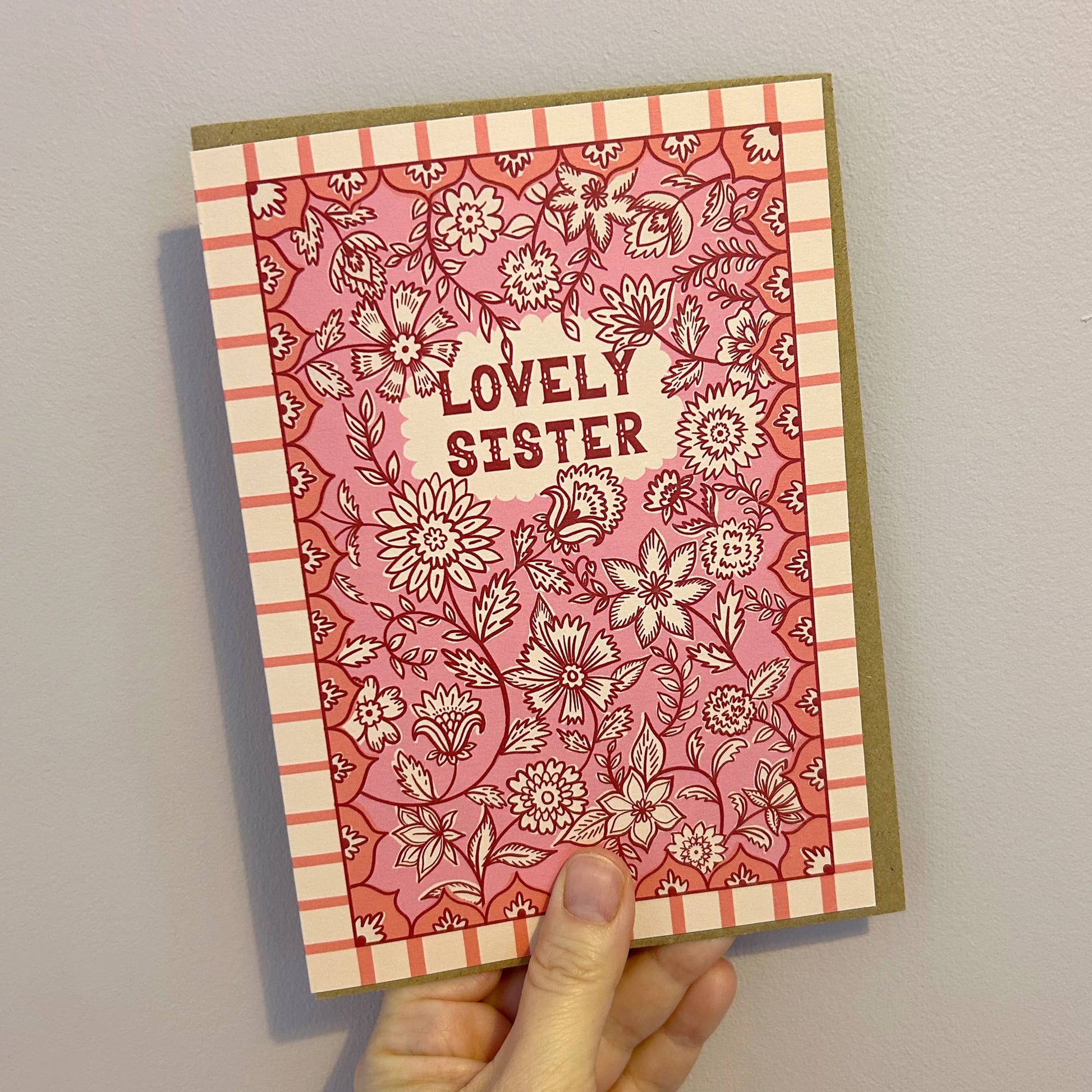 Hand-lettered 'Lovely Sister' typography on the vibrant Indian floral greeting card