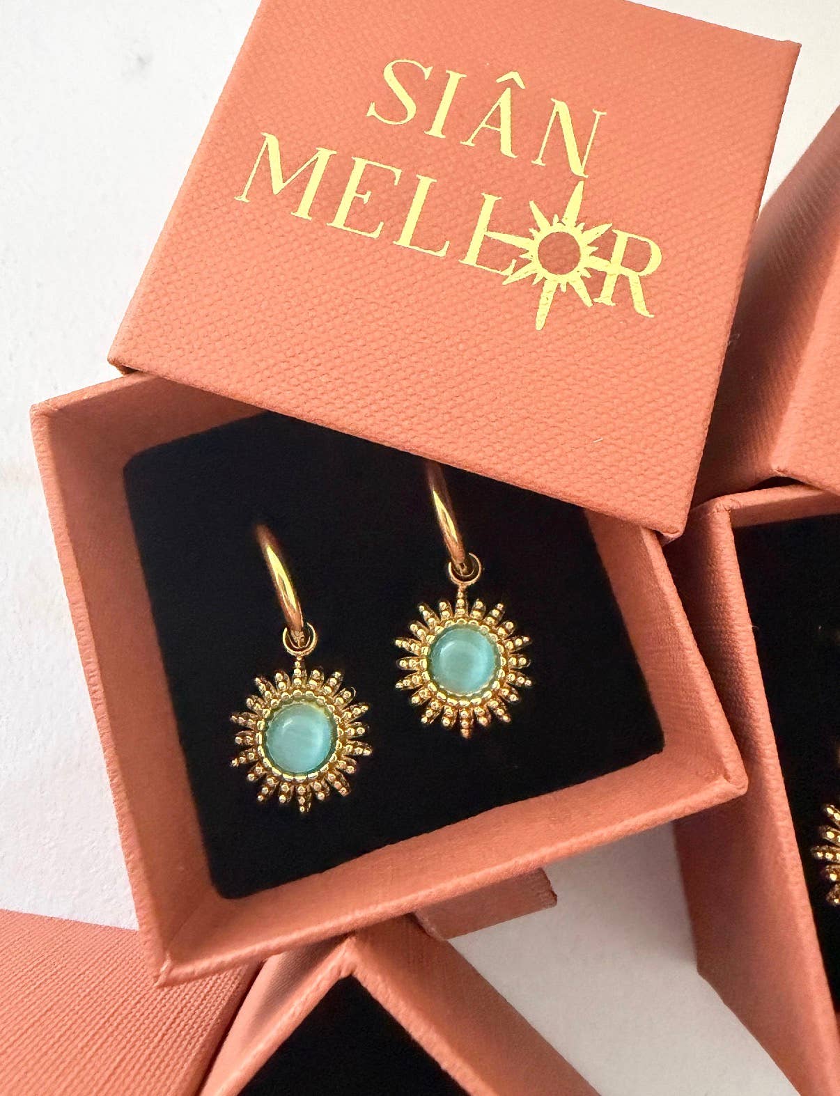 Close up of blue 18k gold plated sun hoop earrings