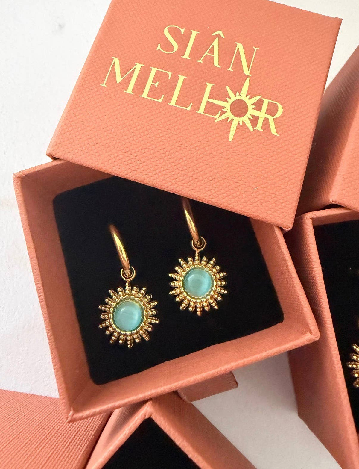 Close up of blue 18k gold plated sun hoop earrings