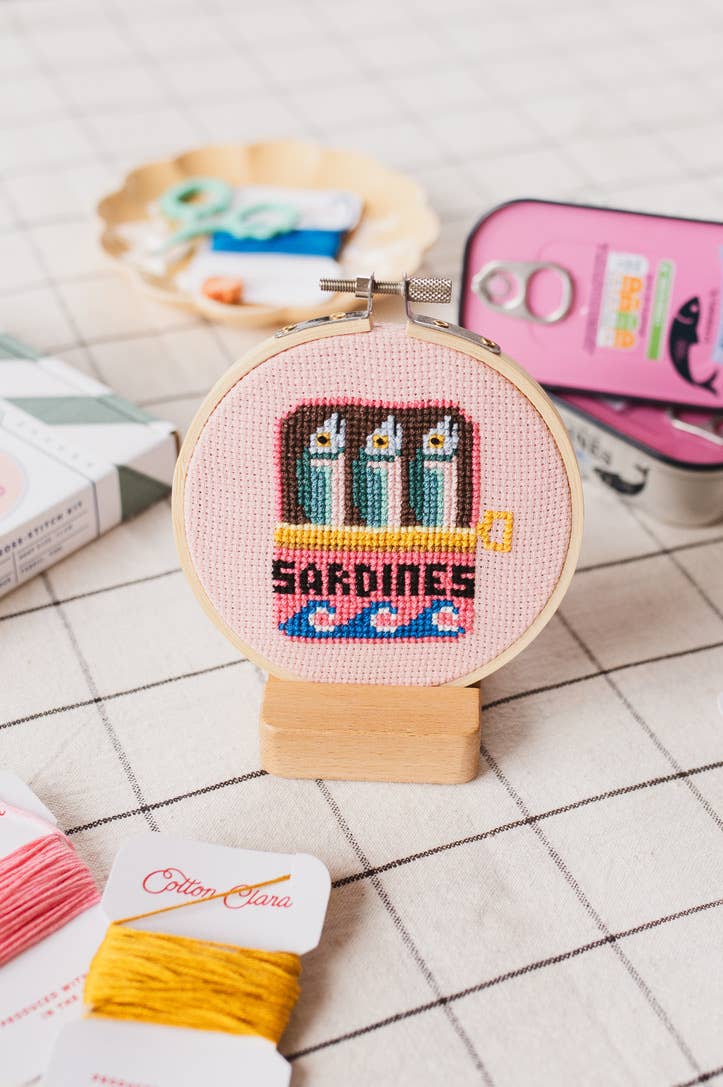 Sardines Cross Stitch Kit for beginners, featuring a 4-inch wooden hoop, coloured Aida fabric, embroidery thread, and eco-conscious packaging. Made in UK.