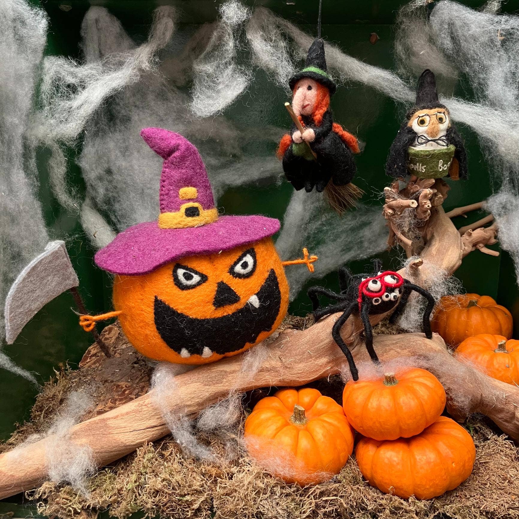 Halloween-themed decorations including a jack-o'-lantern, witches, and pumpkins on a branch with cobwebs.