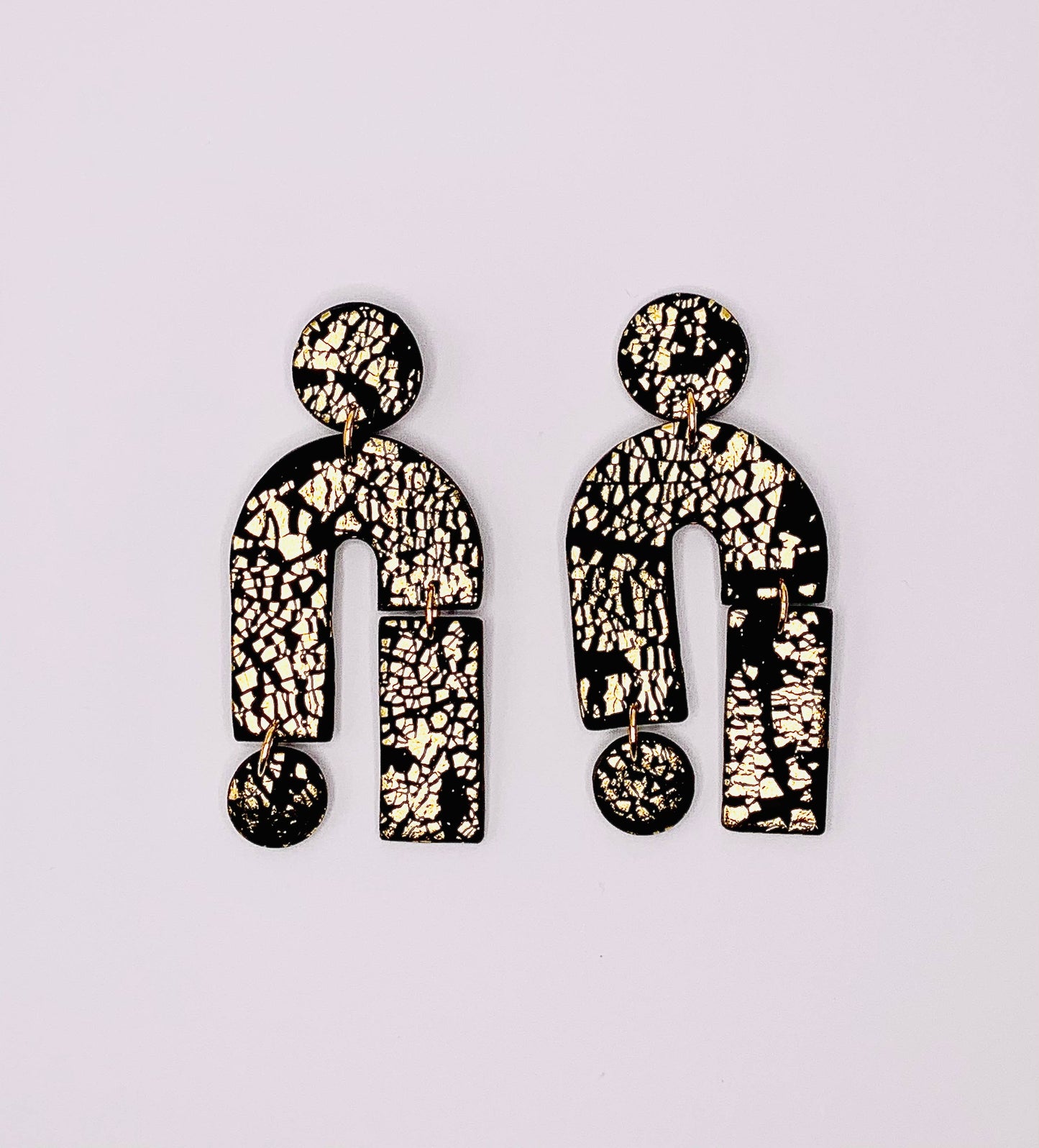 Close-up of a single All that Glitters statement earring worn, highlighting its lightweight black and gold polymer clay design.