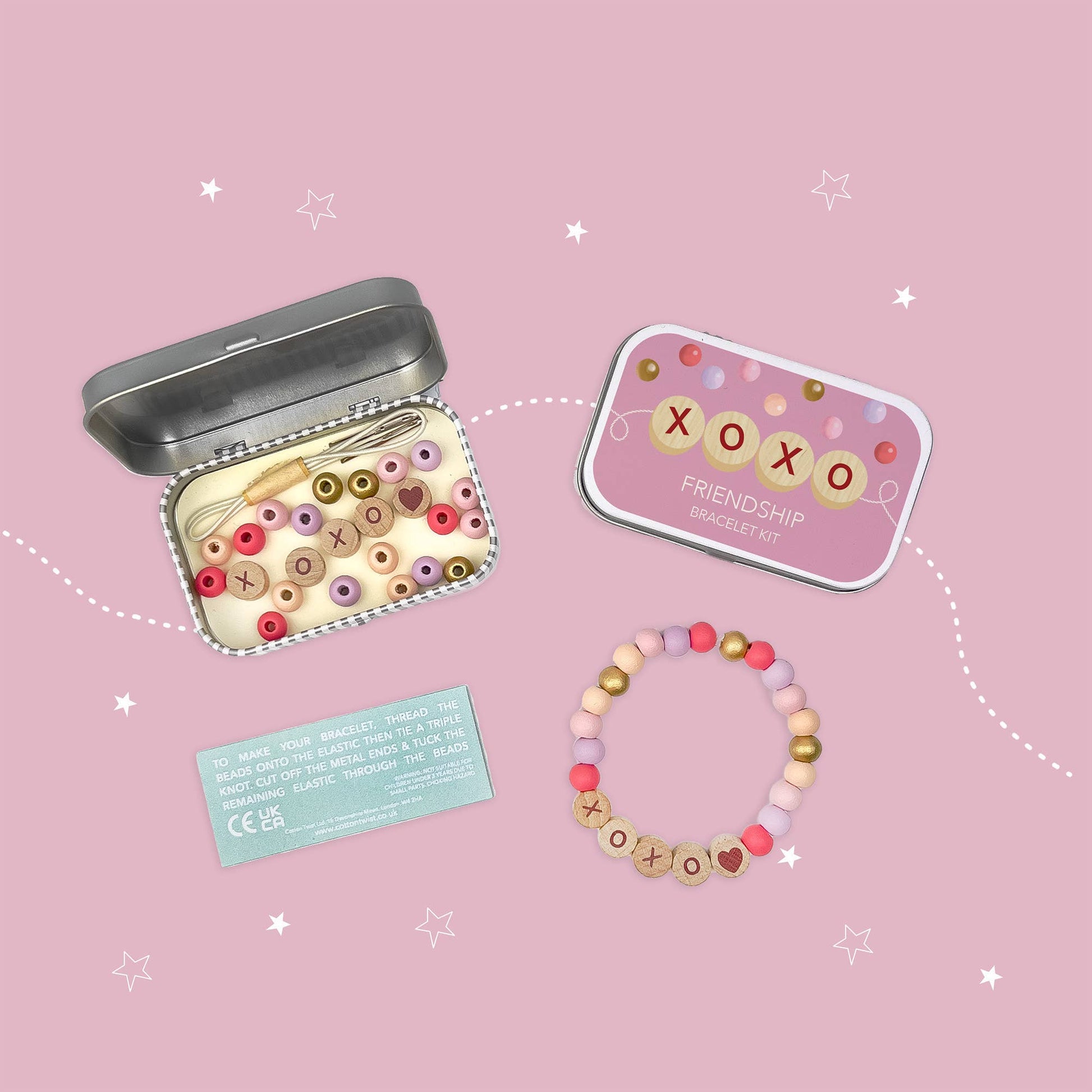 Colorful beaded bracelet with 'xoxo' symbols on a pink background, accompanied by a tin box and card.