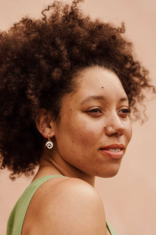 Model wearing Swirl Gold Hoop Earrings, showcasing the lightweight acrylic and sustainably sourced wood design, 15mm diameter hoops.