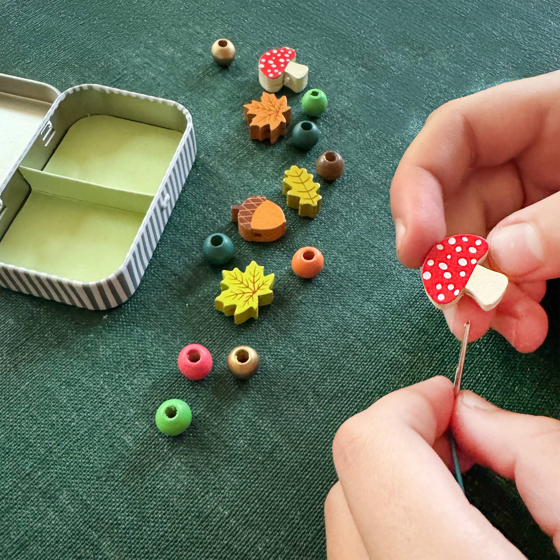 A beautiful gift tin containing elastic &amp; beads to create a beautiful wooden forest-themed bracelet. The elastic comes with metal ends to help children add beads with ease. The tin can be used to store the bracelet, or a special trinket