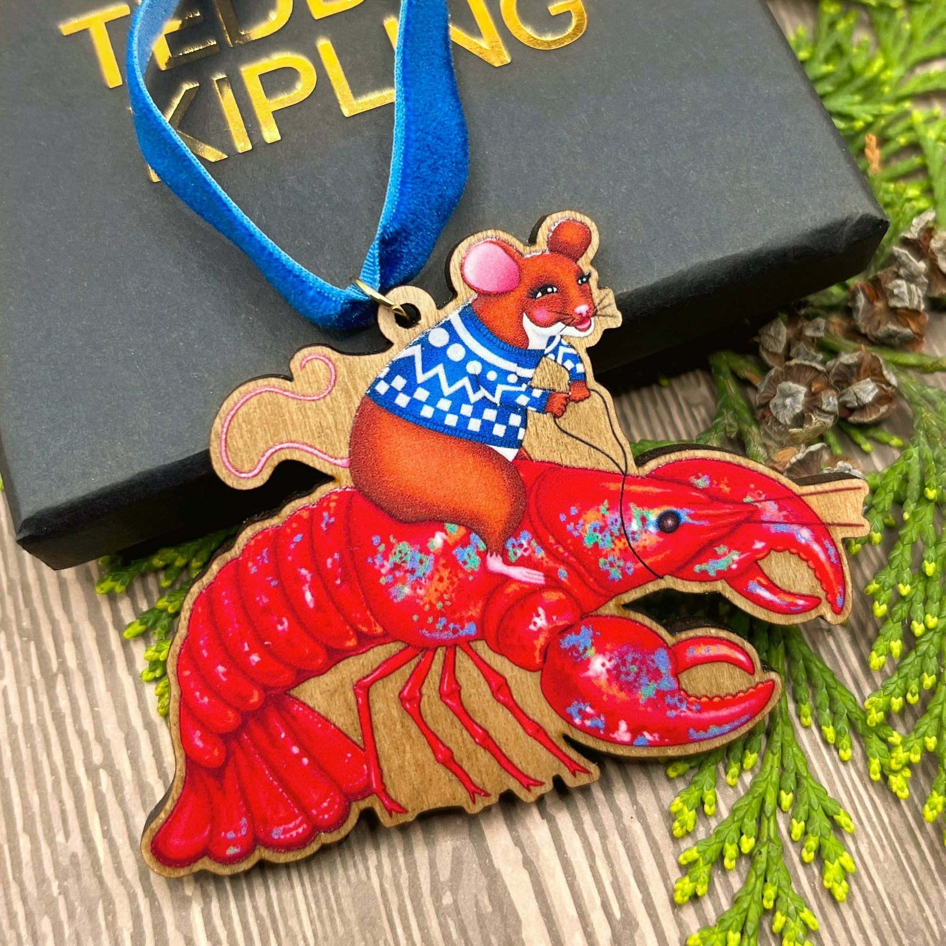 Mouse On A Lobster wooden Christmas tree decoration with Teddy & Kipling illustration, sustainably certified cherry wood, gold-plated ring, and royal blue velvet ribbon.