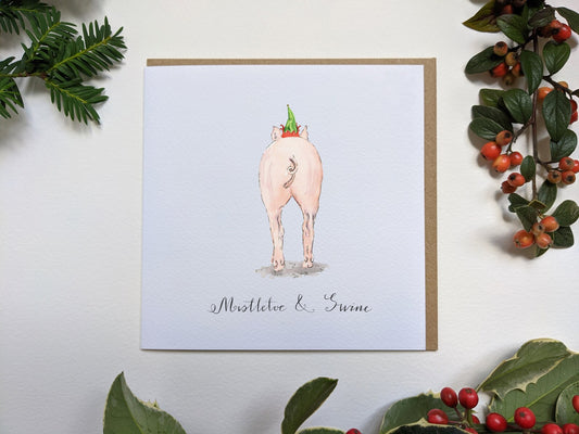 Close-up of Mistletoe & Swine Christmas card showing textured cardstock and whimsical pig illustration by Jessica Kendrew.